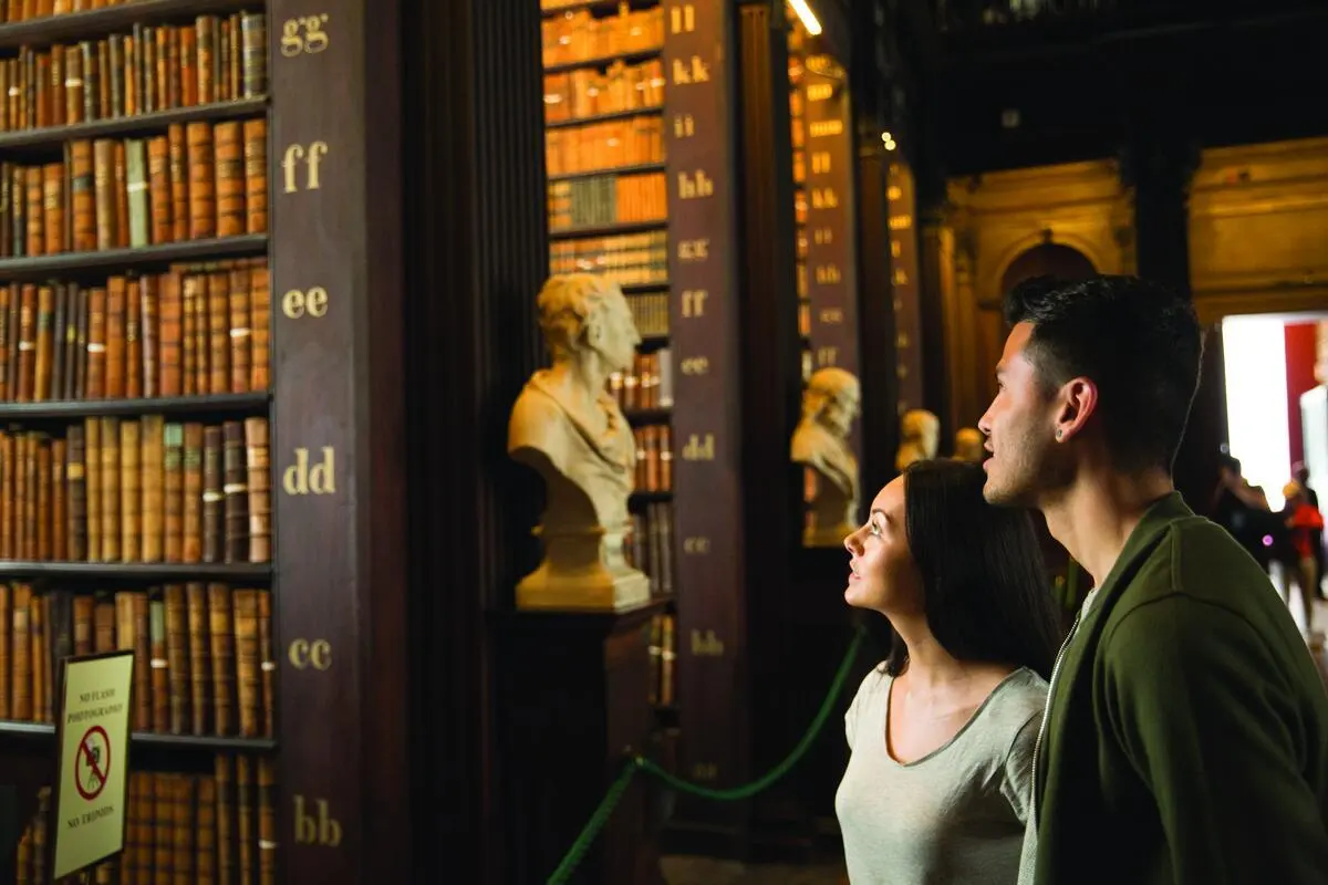 Visitors looking up at the marble busts in the Long Room library at Trinity College Dublin
